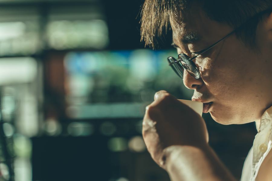 男子側臉低頭啜飲咖啡