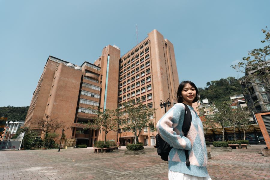 女學生背著包站在校園紅磚大樓前