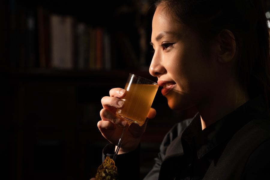 女子在暗色空間裡品嘗調酒
