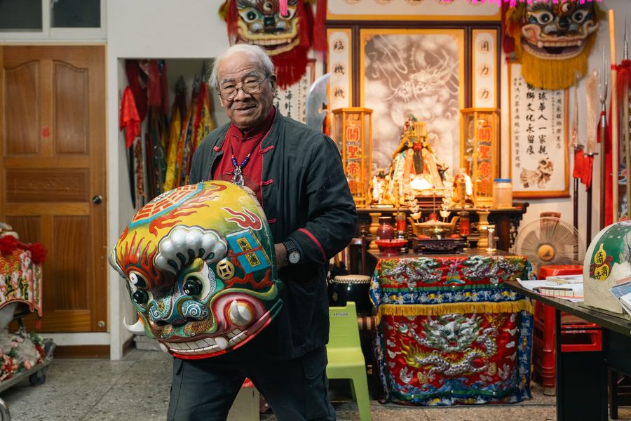老師傅抱著彩繪獅頭站在神明廳前