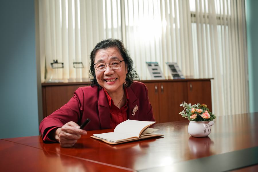 女士在辦公室書桌前執筆微笑