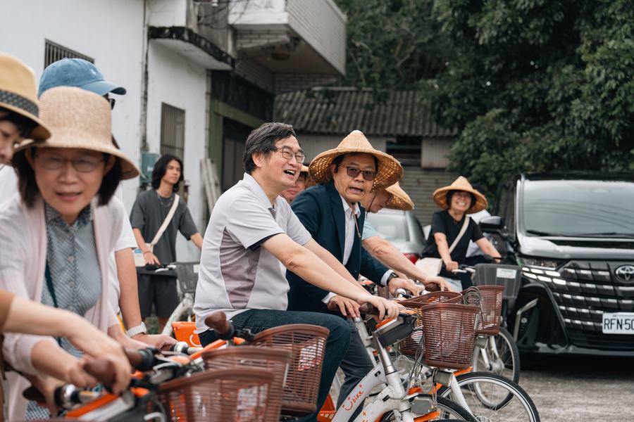 一群戴著斗笠與帽子的參加者騎上共享單車，準備出發走讀